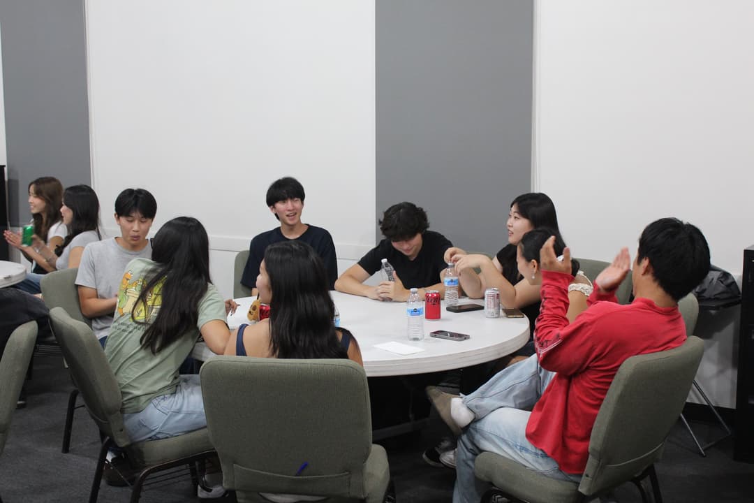 Students talking around a table at a 1128 College gathering